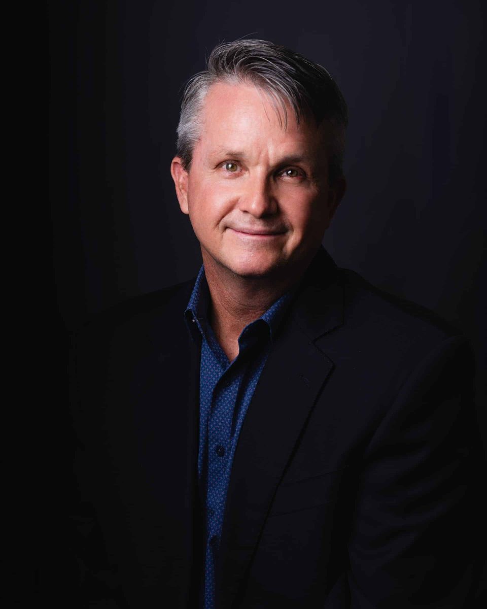 Barney Connaughton, attorney-mediator, in a dark jacket against a dark background.